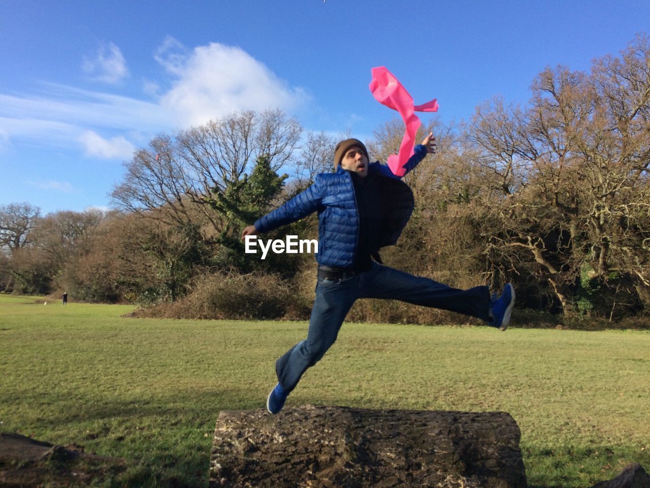 Full length of man with arms outstretched jumping on field