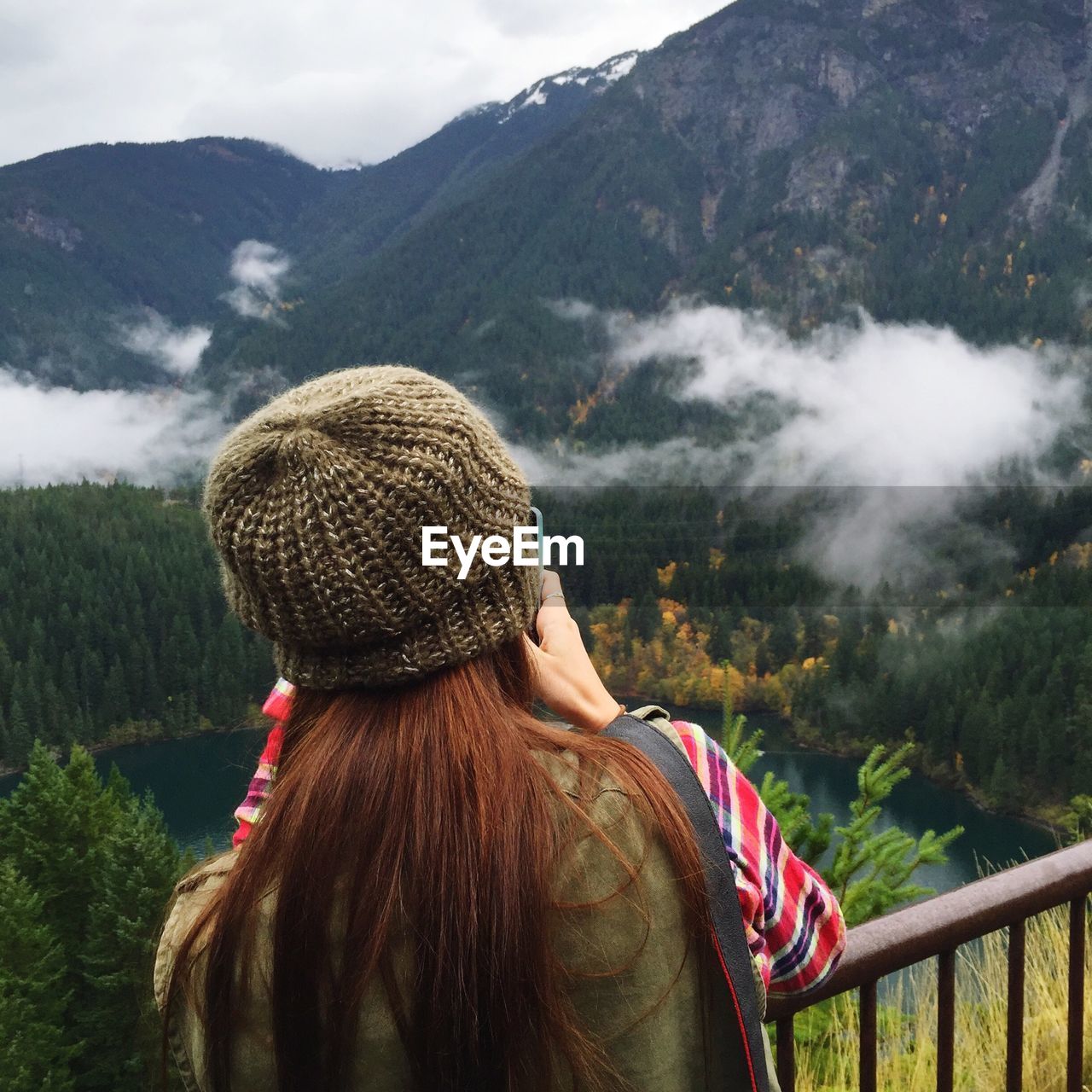 Rear view of woman with knit hat standing against mountain