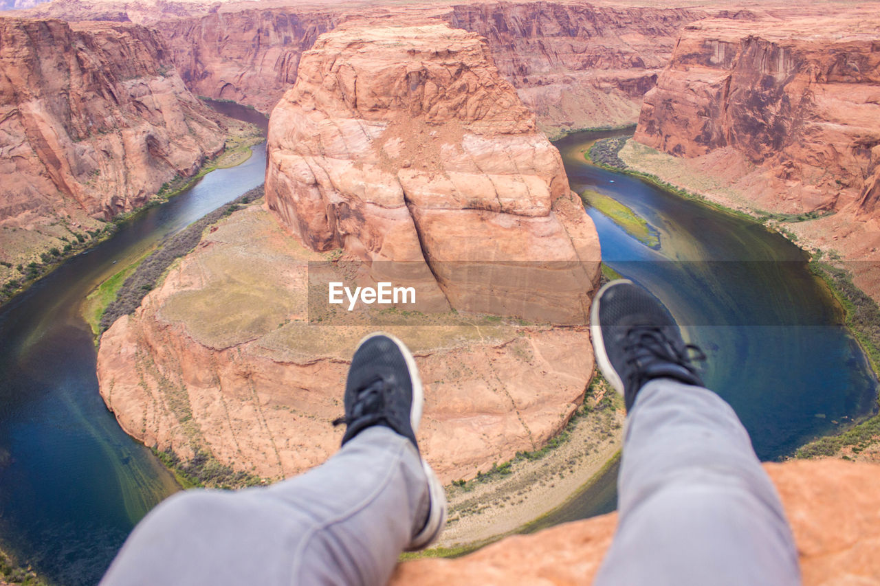 Low section of man sitting on cliff at glen canyon