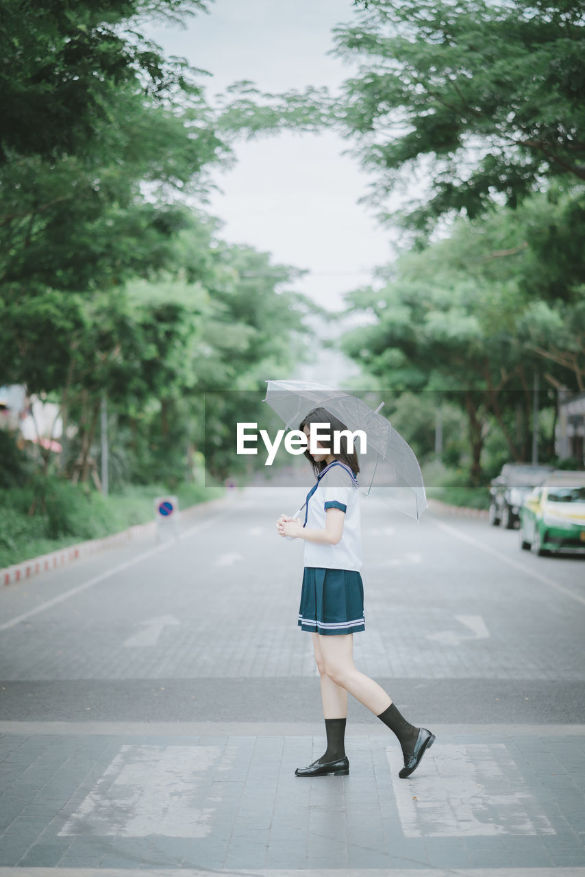 SIDE VIEW OF WOMAN ON ROAD IN CITY