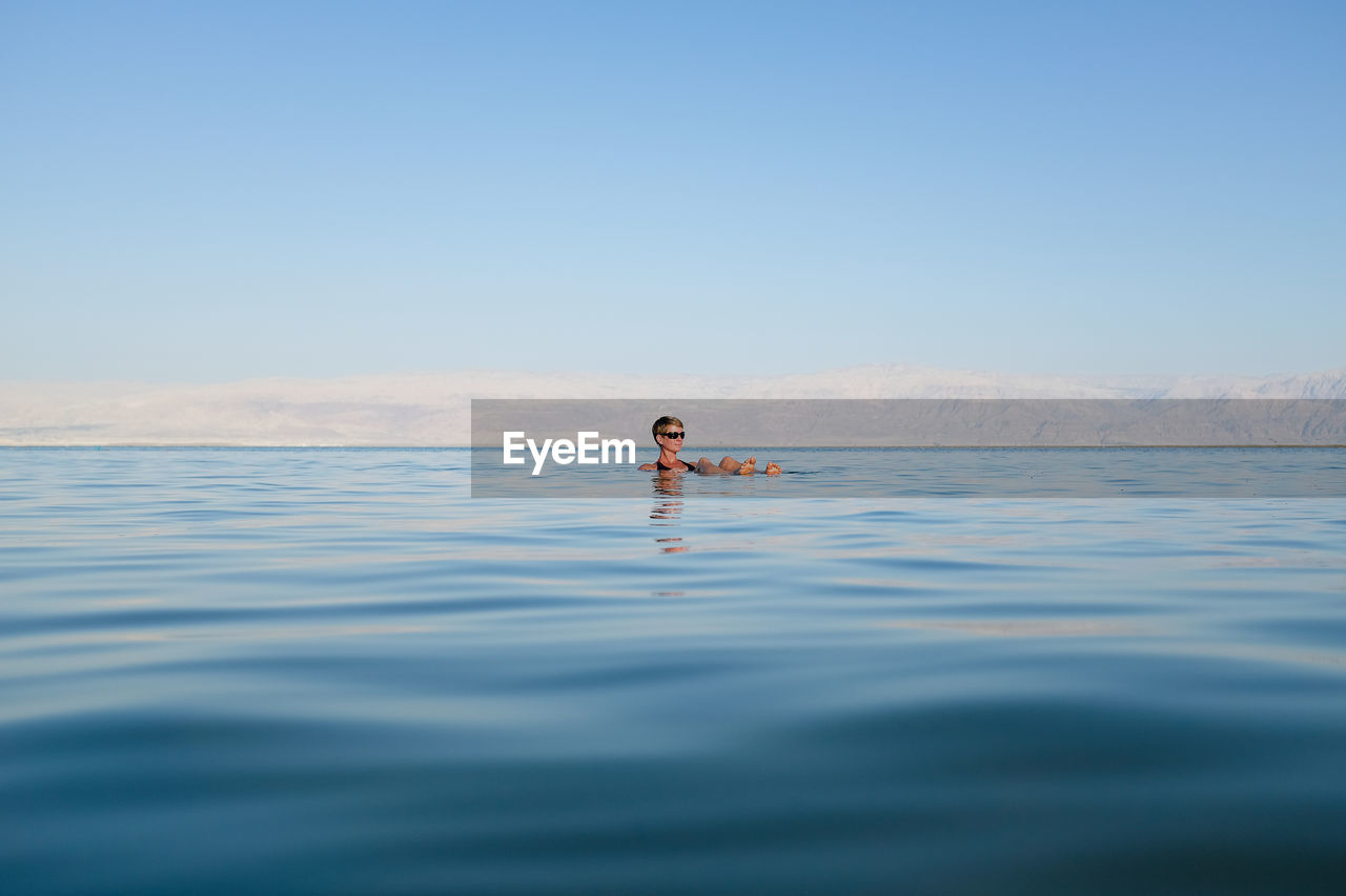 Woman relaxing in sea against sky