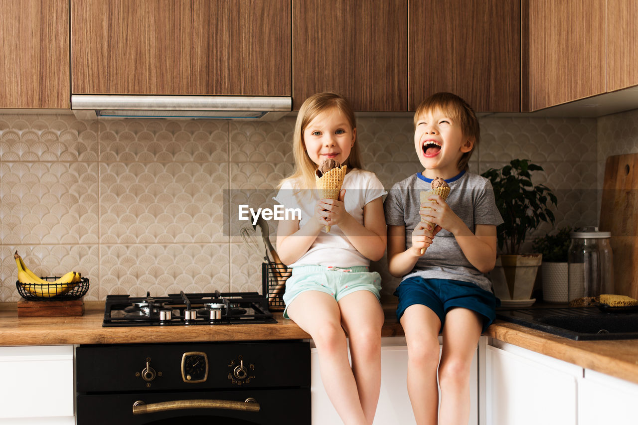 Siblings eating ice cream at home