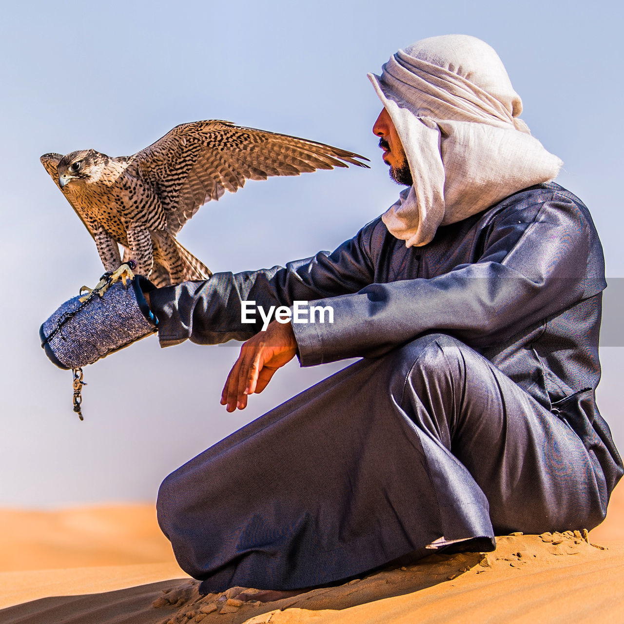 Rear view of man sitting on desert dunes