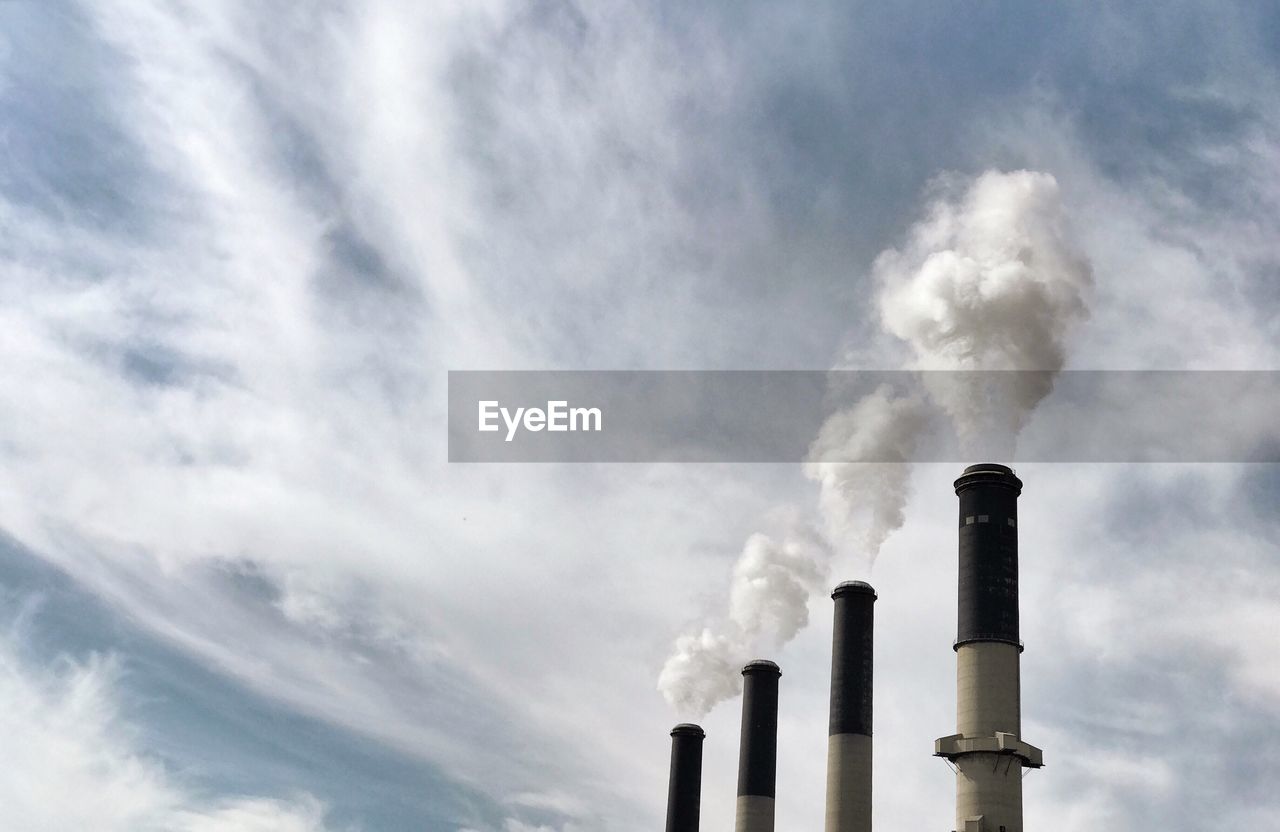 Low angle view of smoke stacks against sky