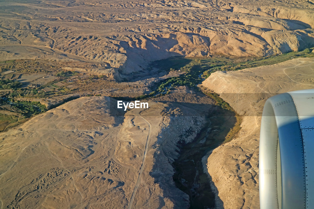 HIGH ANGLE VIEW OF AIRPLANE FLYING ABOVE LANDSCAPE