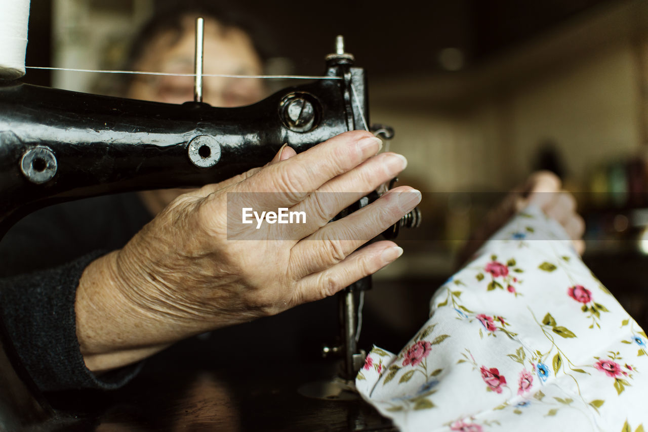 Close-up of old woman using sewing machine
