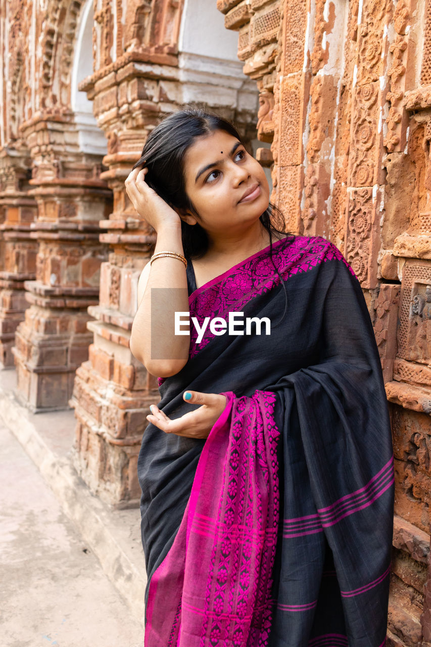 A pretty indian woman in saree near a terracotta temple of west bengal