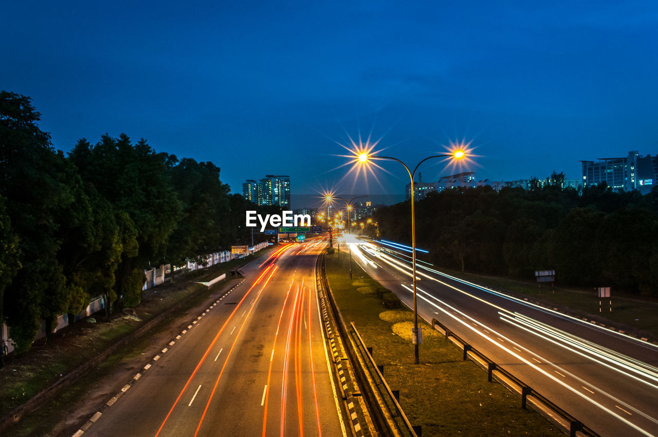 Light trails on road against sky at night