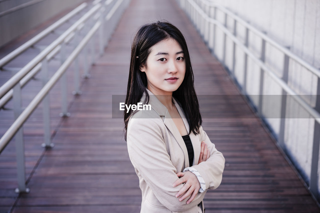 Confident beautiful chinese business woman with arms crossed standing on runway. entrepreneur