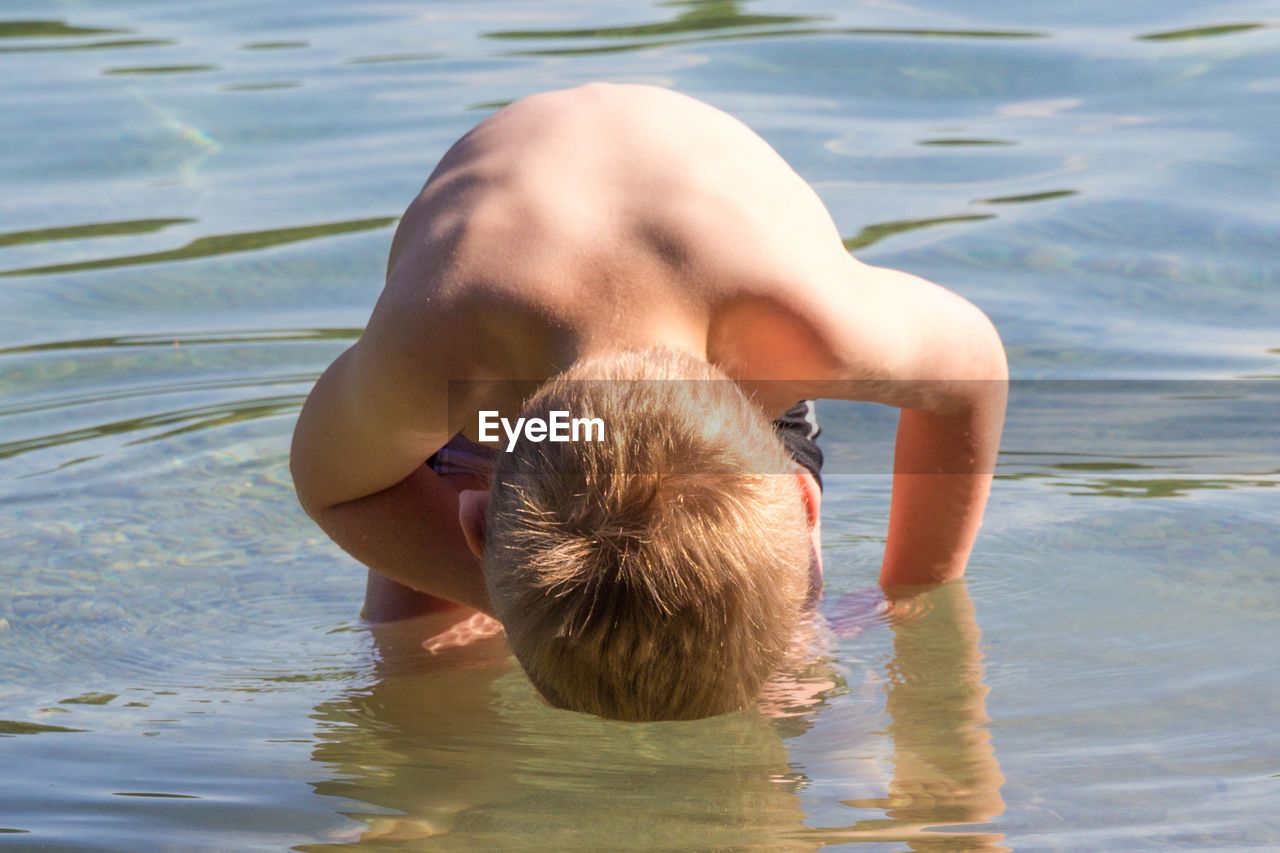 Close-up of shirtless boy bending in sea