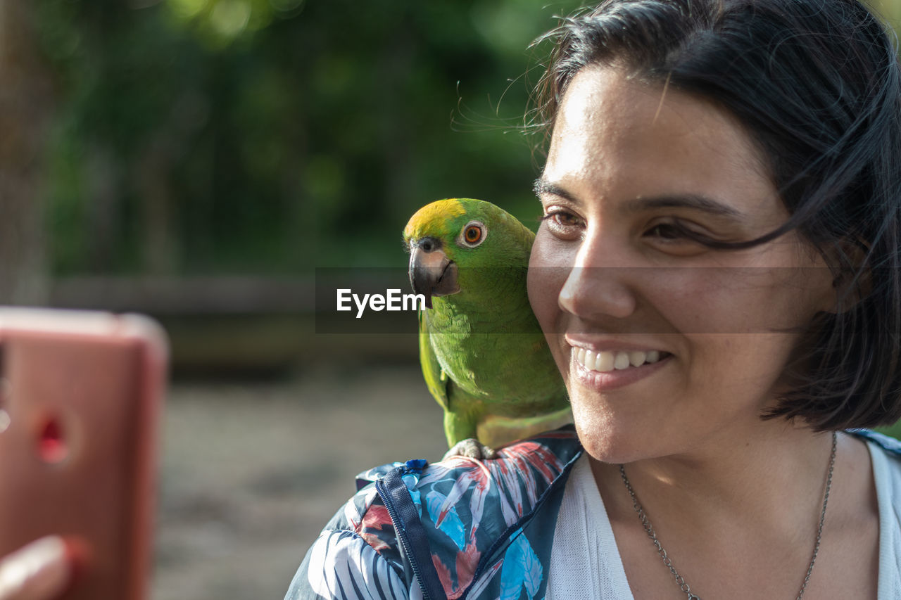 Woman performs a selfie with a parrot in the jungle of the orinoco delta in venezuela