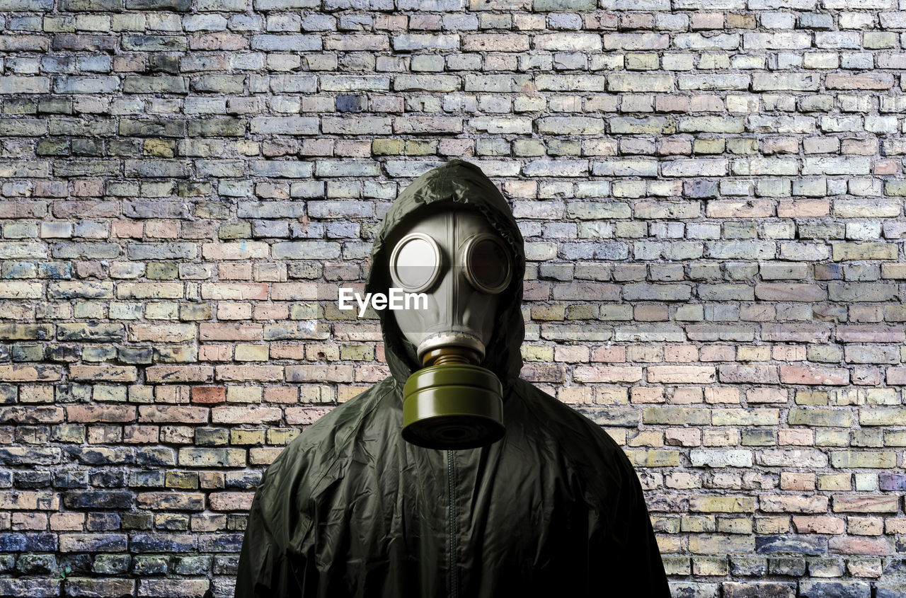 gas mask, clothing, costume, mask, brick, wall - building feature, one person, wall, brick wall, art, personal protective equipment, disguise, obscured face, men, protection, security, standing, architecture, protective mask - workwear, waist up, mask - disguise