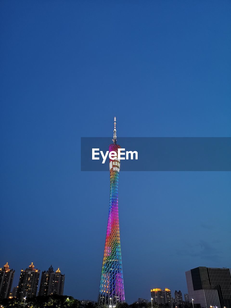 Low angle view of illuminated tower against clear blue sky