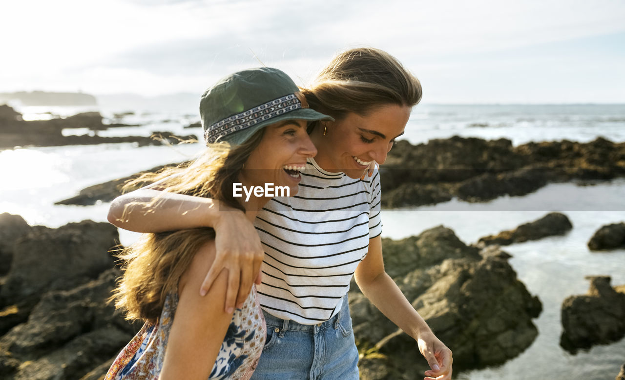 Cheerful young sisters enjoying at beach during weekend