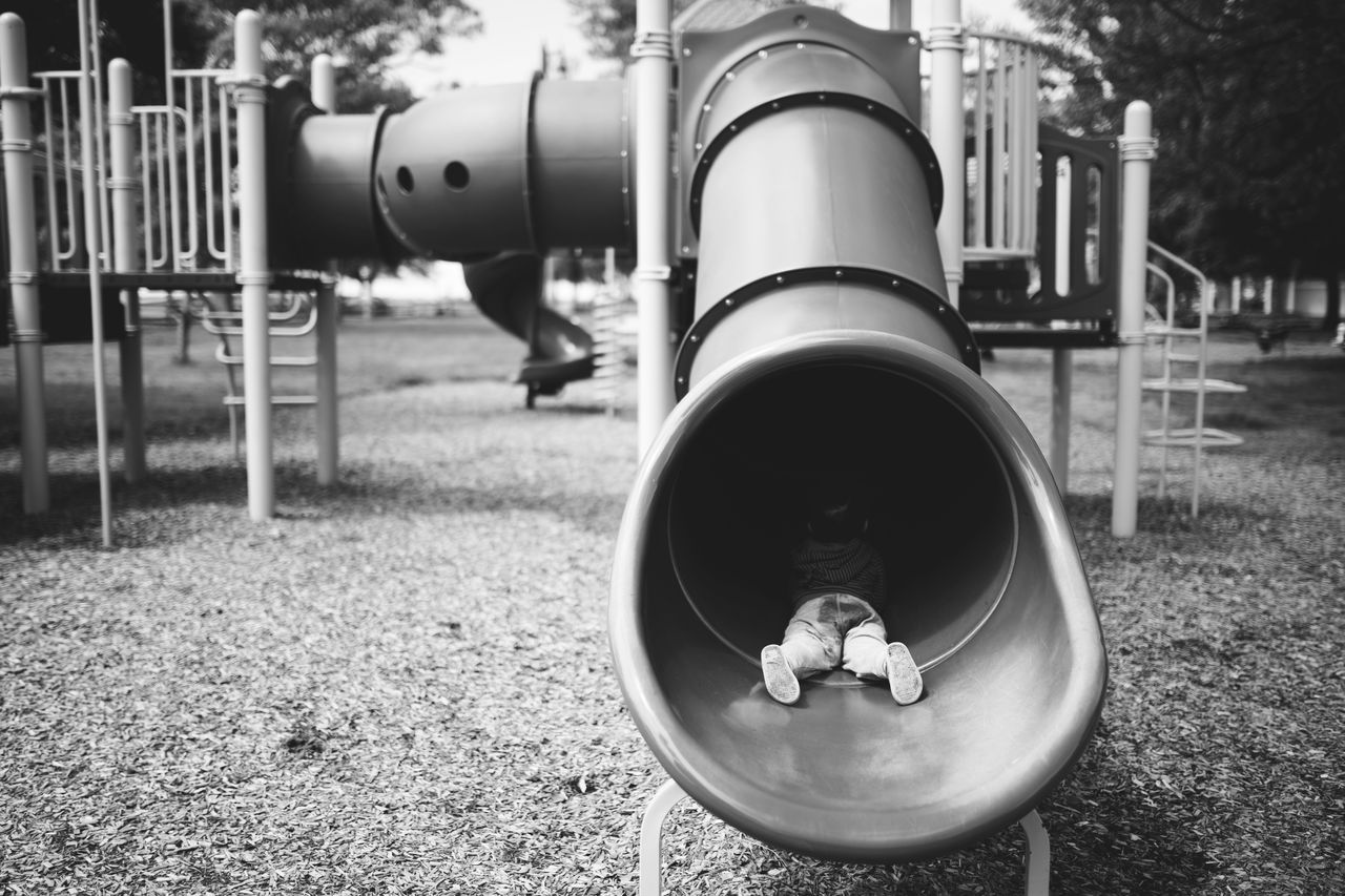 Full length of boy lying in slide at playground