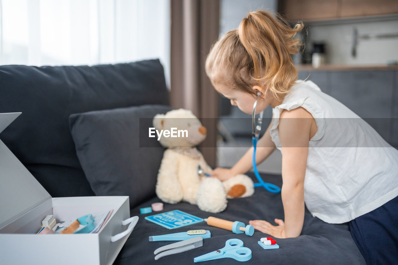 side view of woman using digital tablet while sitting on sofa at home