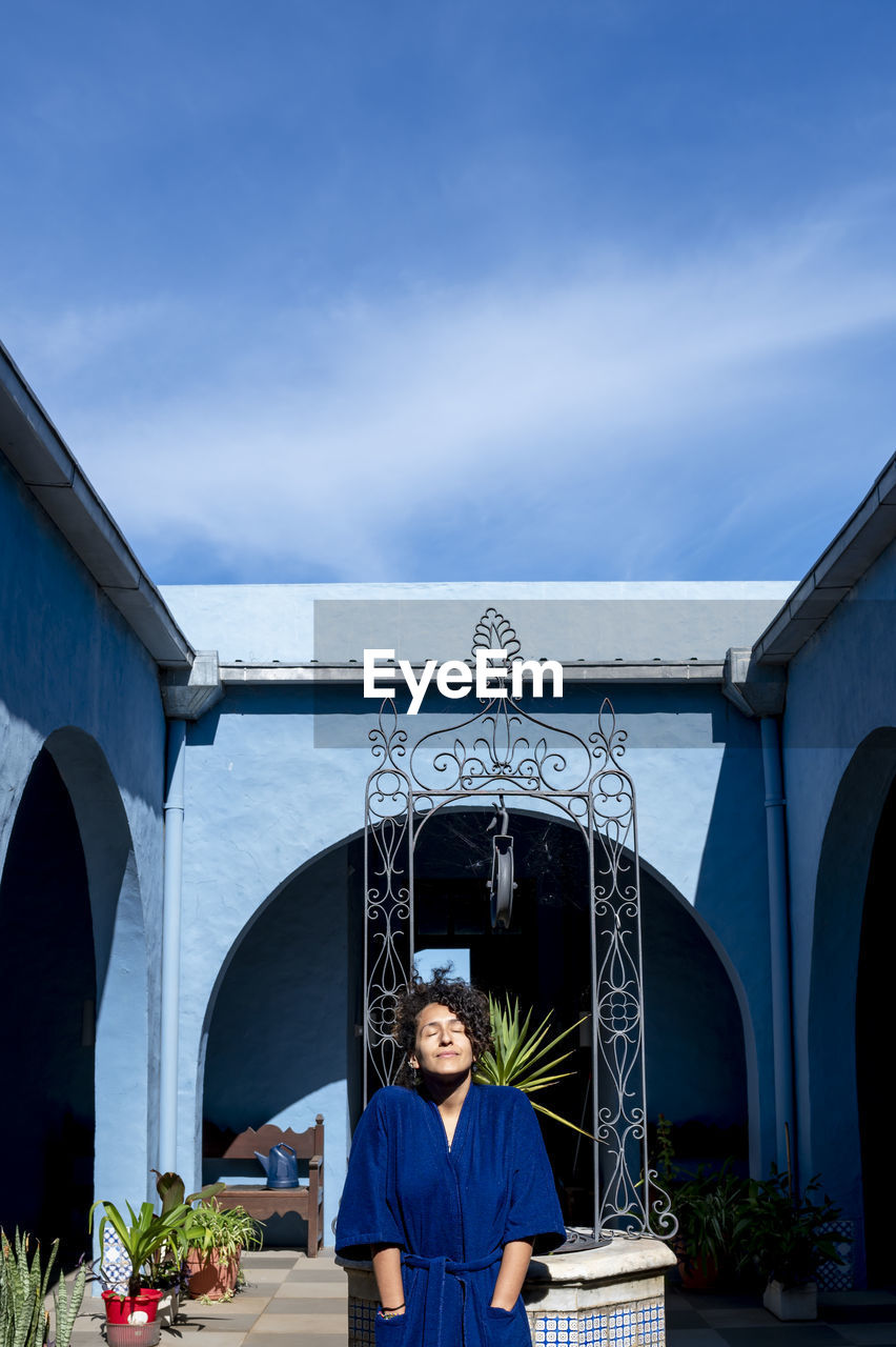 Woman posing in robe outdoors in a countryside house.