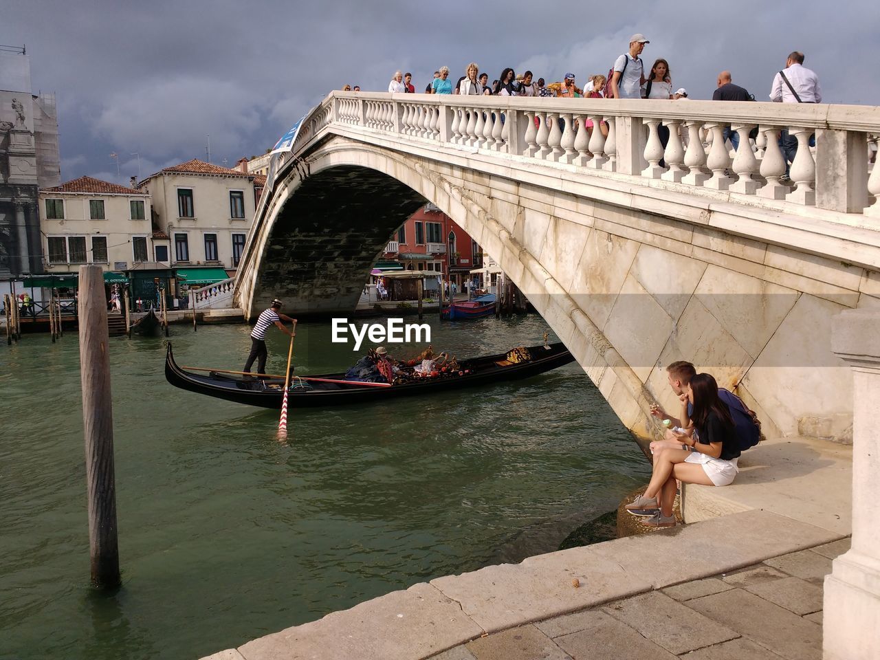 People sitting on bridge over river in venice