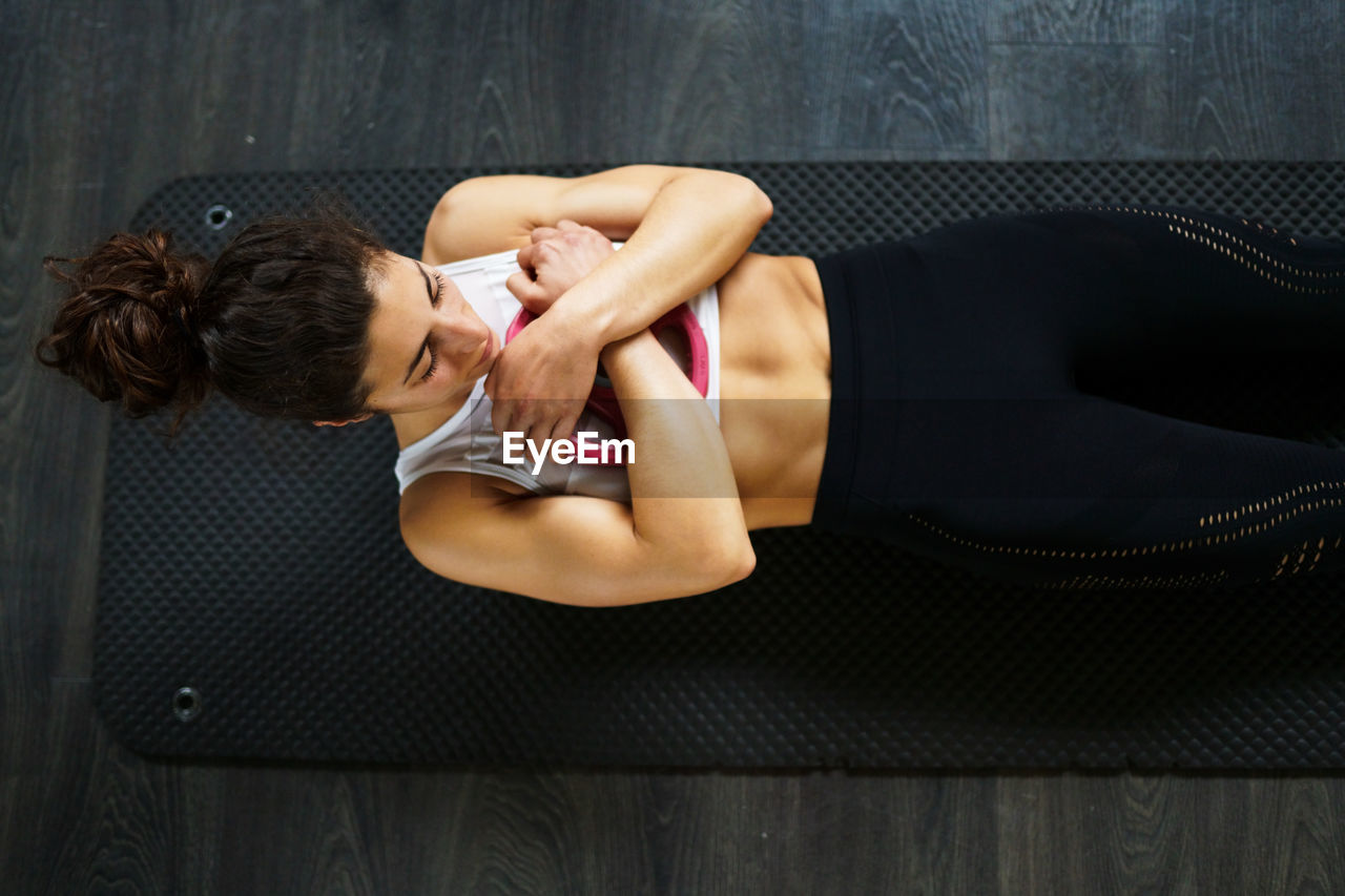 High angle view of woman exercising on floor at gym