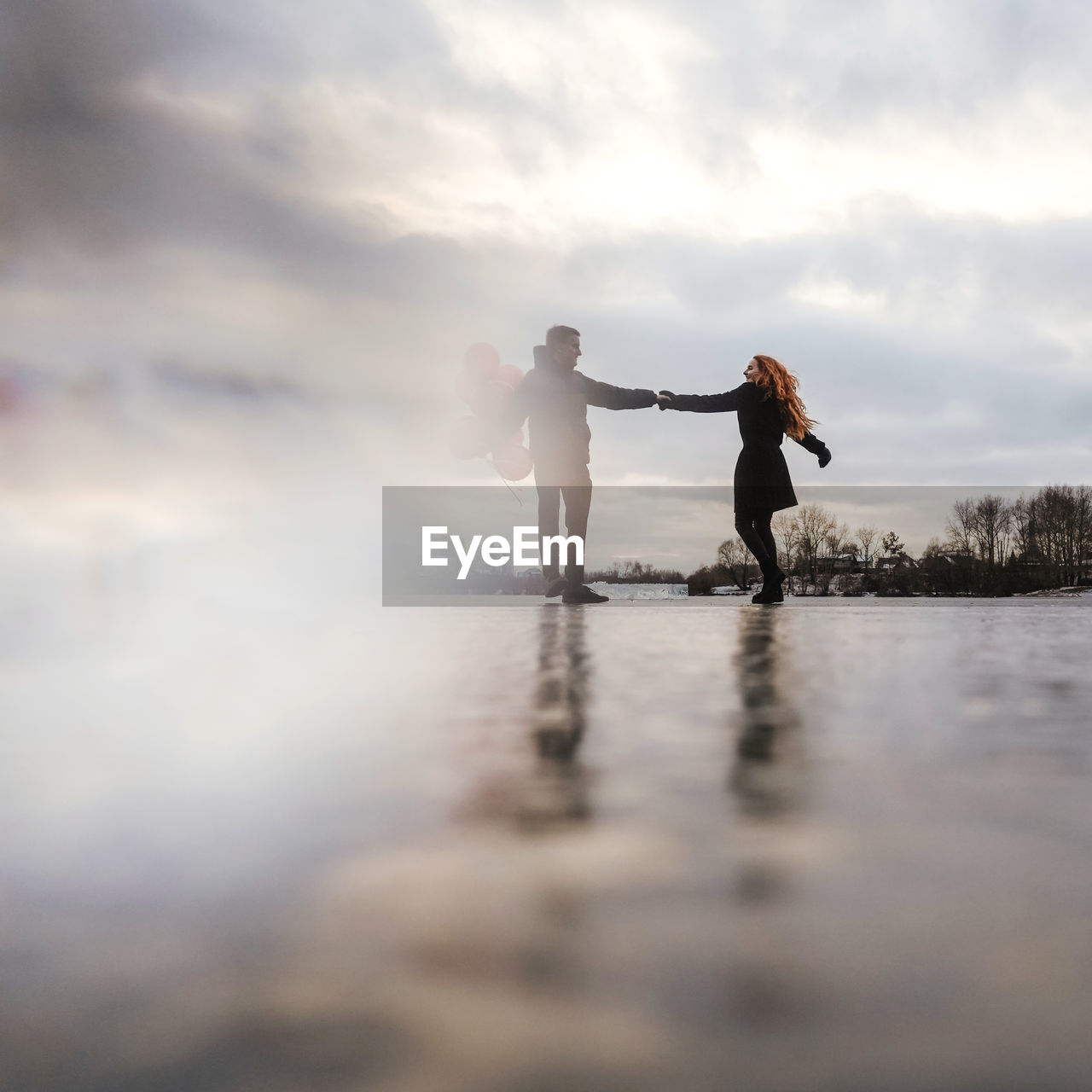 Full length of couple holding hands against sky