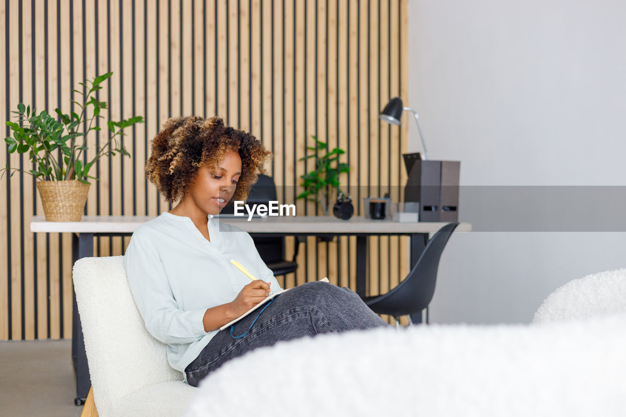 young woman using laptop while sitting on bed