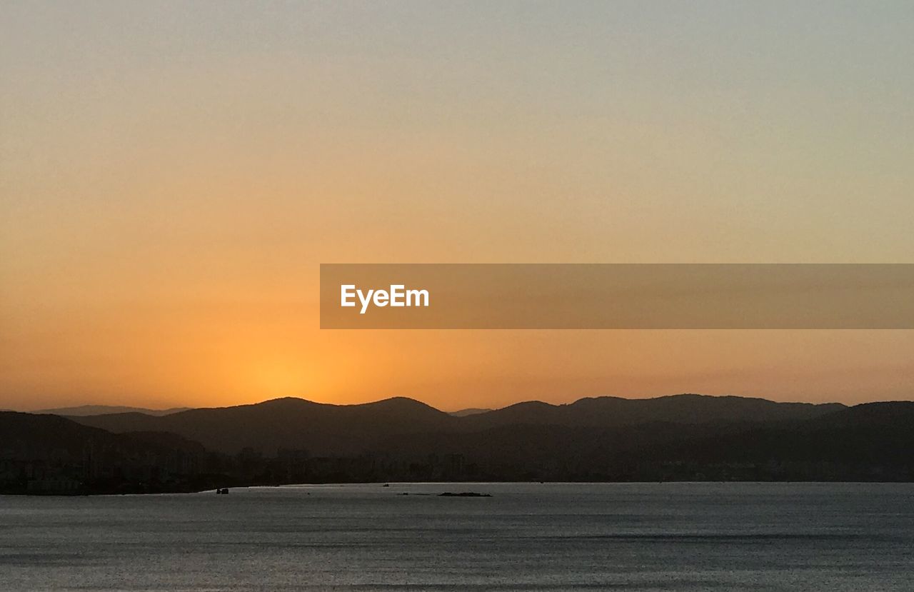 SCENIC VIEW OF LAKE AGAINST SKY AT SUNSET