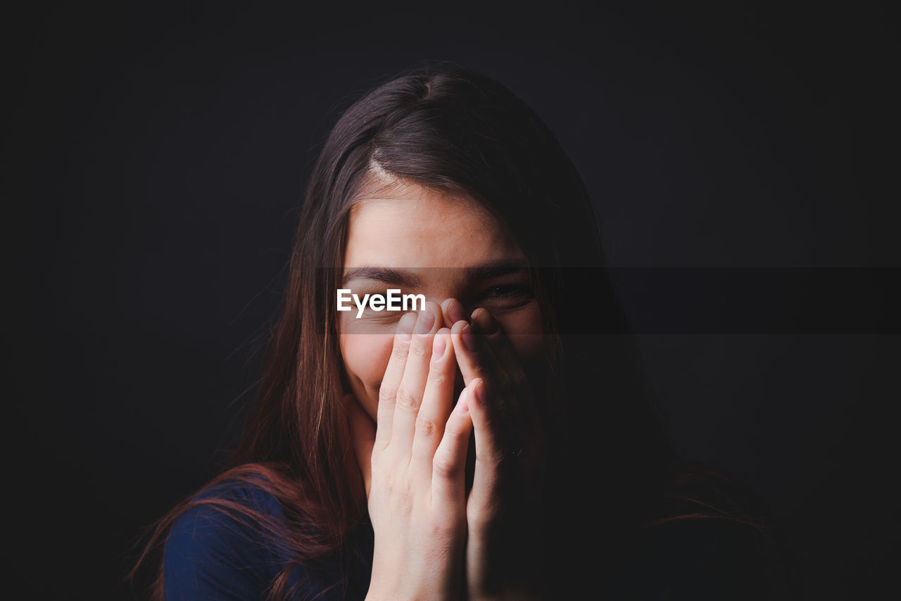 PORTRAIT OF YOUNG WOMAN AGAINST BLACK BACKGROUND