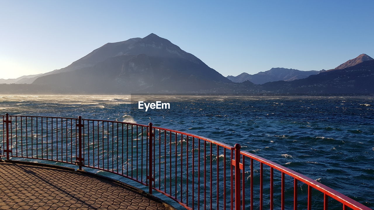 Scenic view of sea and mountains against clear blue sky