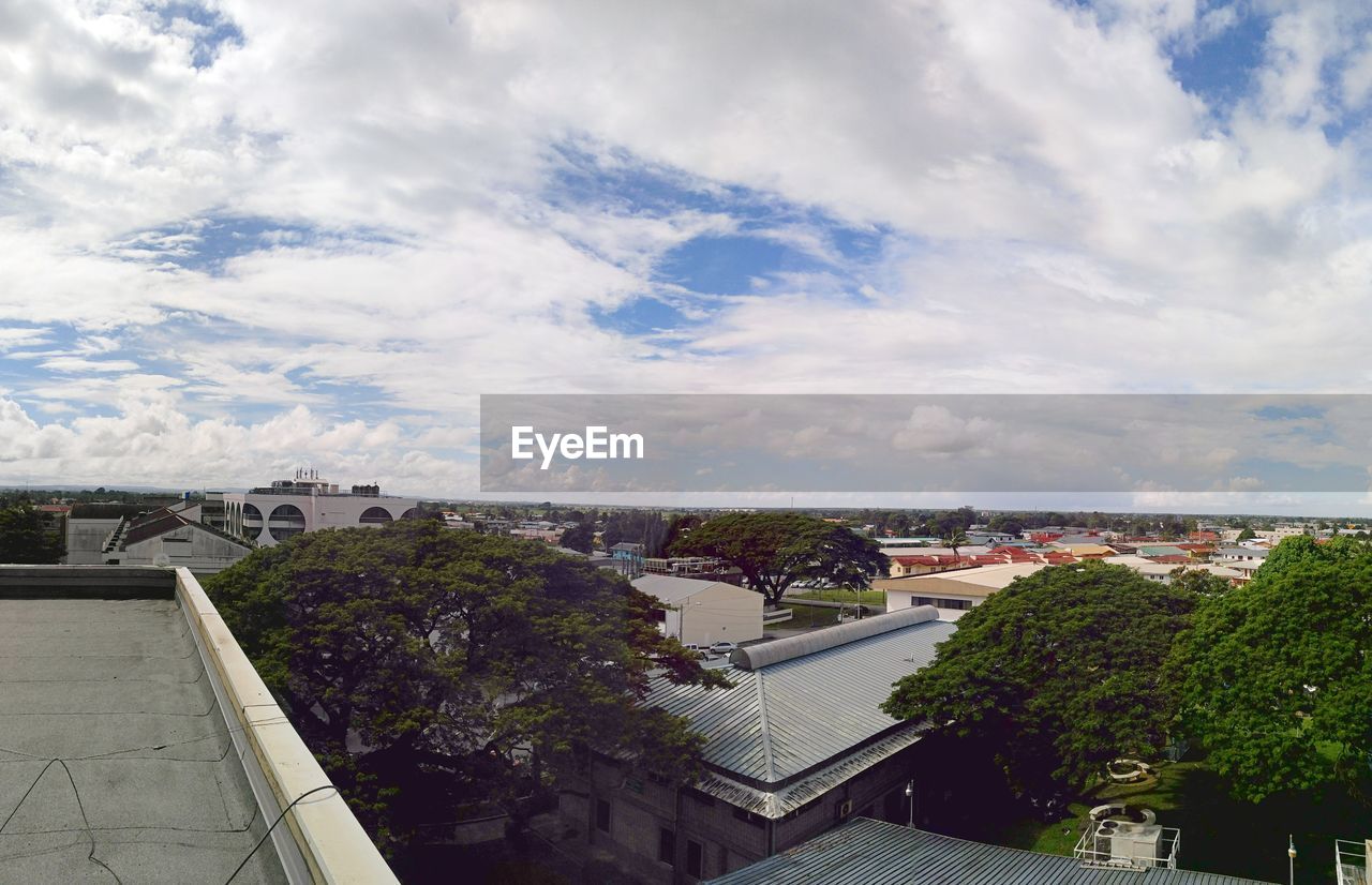 HIGH ANGLE VIEW OF TREES AND CITYSCAPE AGAINST SKY