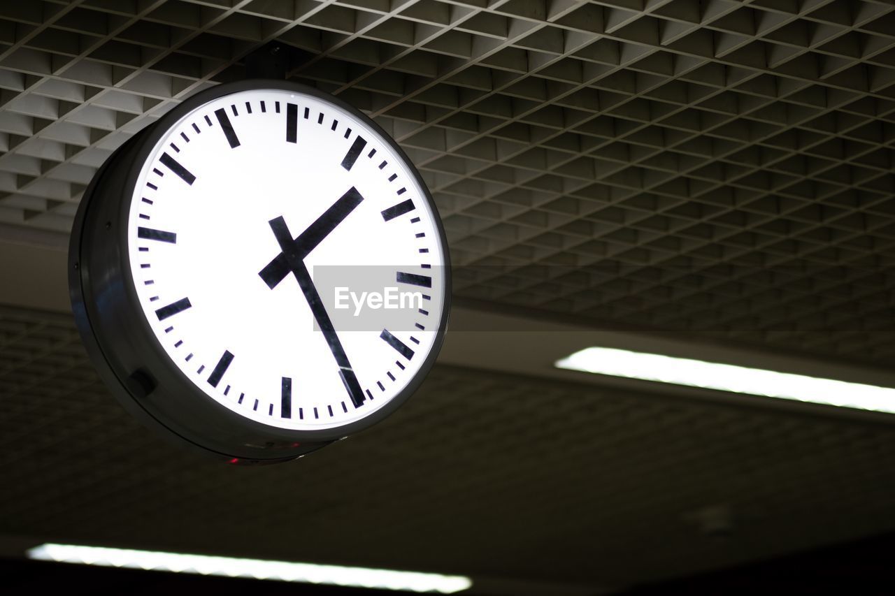 LOW ANGLE VIEW OF CLOCK ON WALL IN ILLUMINATED CEILING