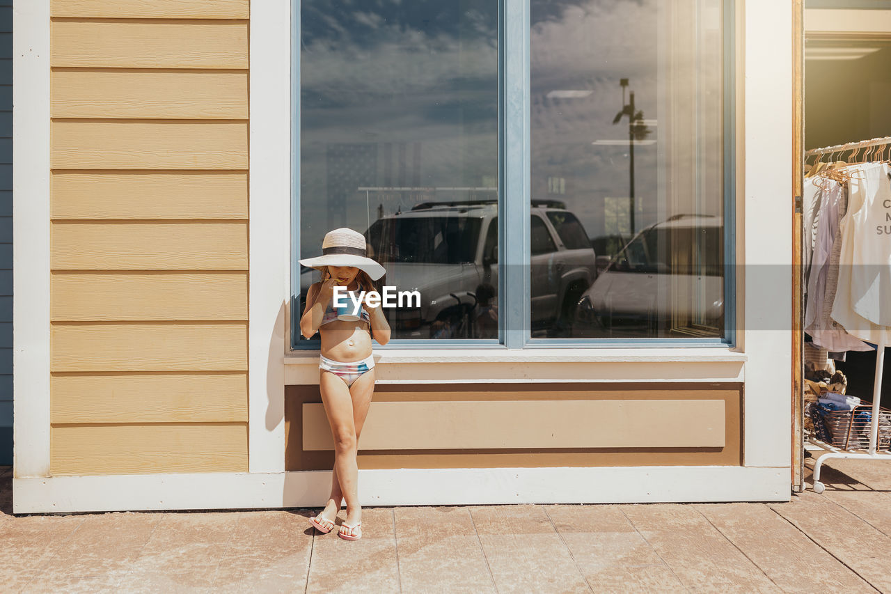 Girl eating ice cream in front of beachfront cafe