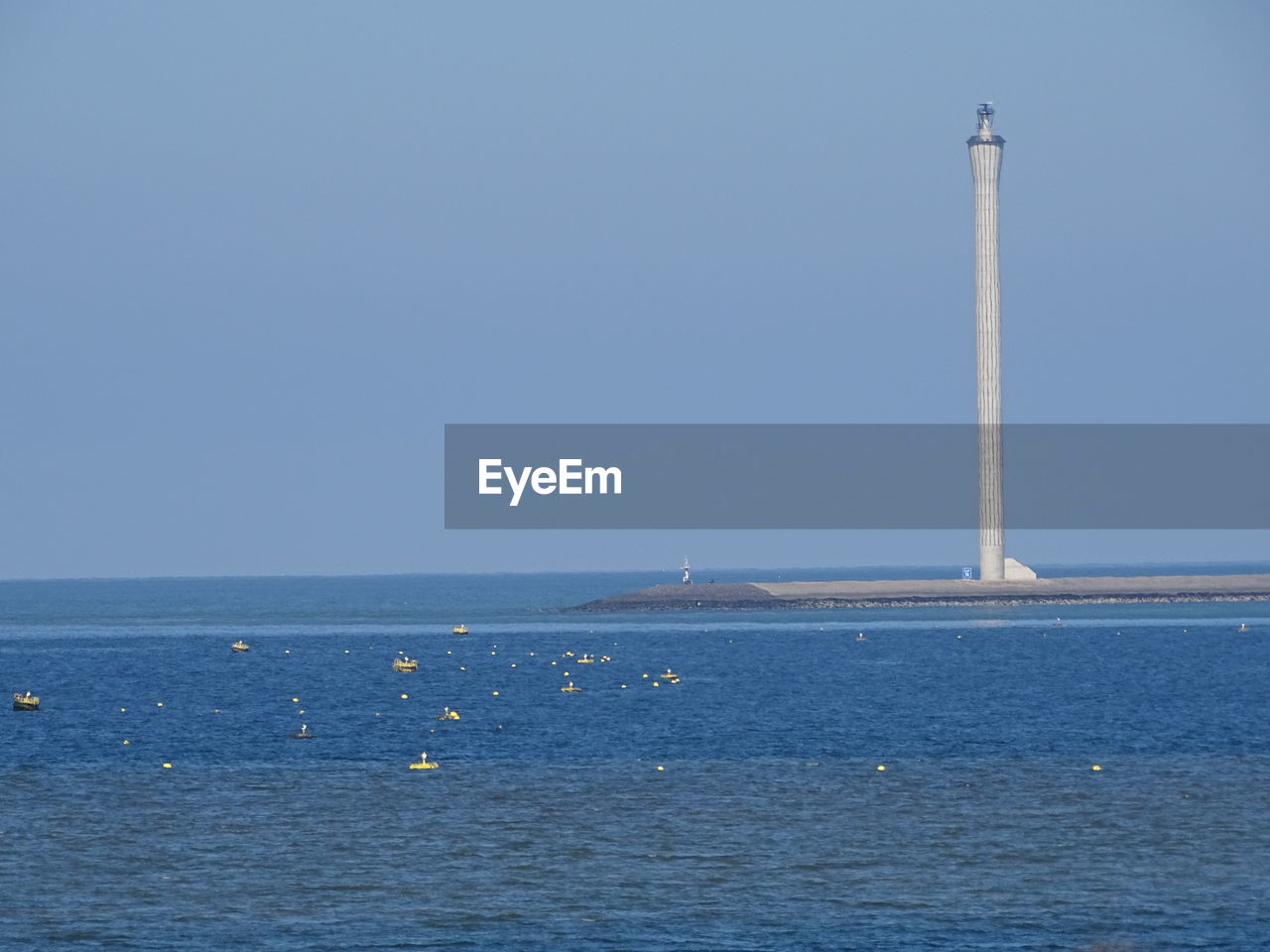 Sailboat in sea against clear blue sky