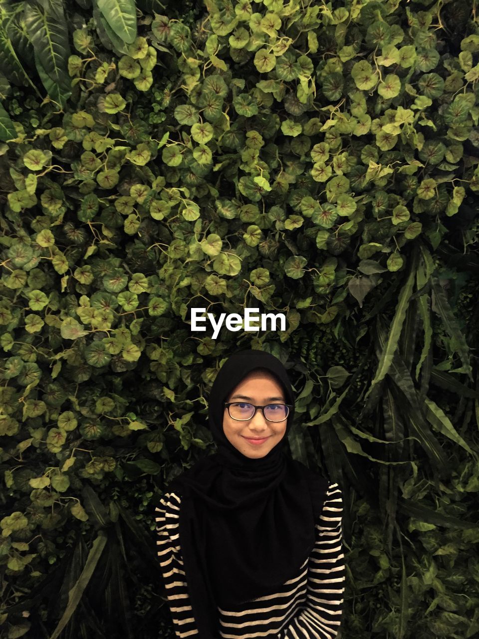 Portrait of young woman against plants