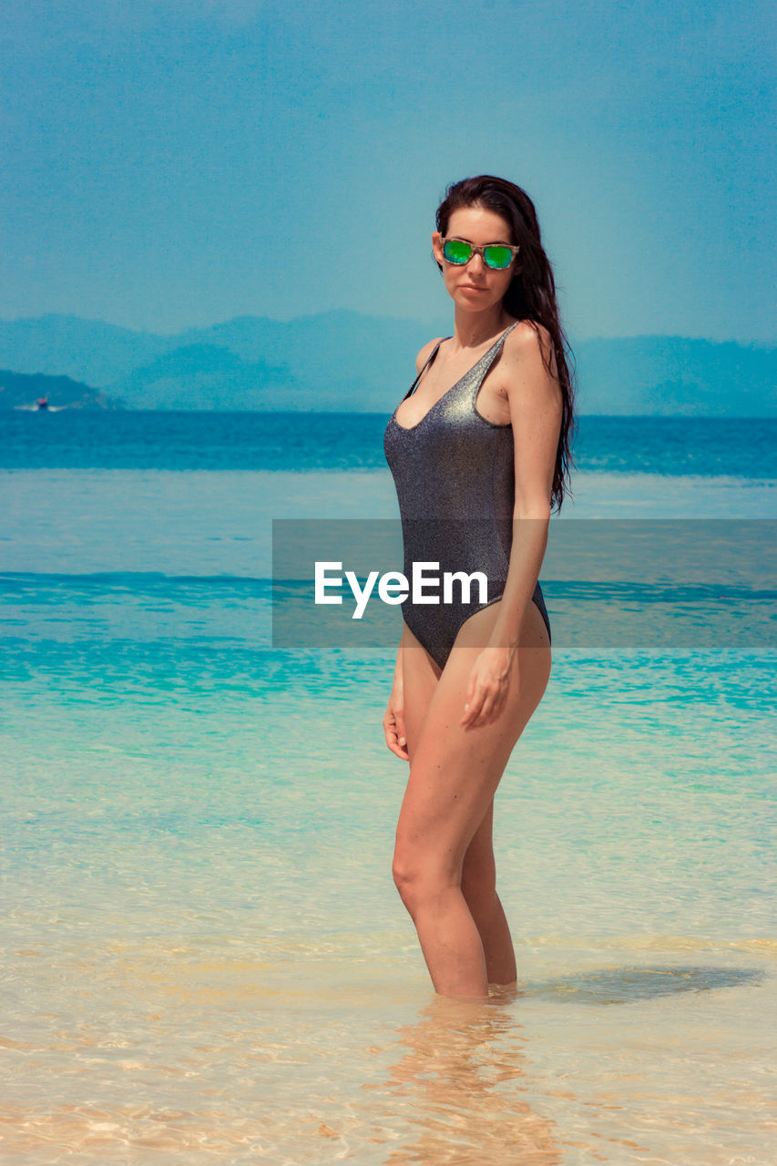 Woman wearing swimsuit standing in sea at beach