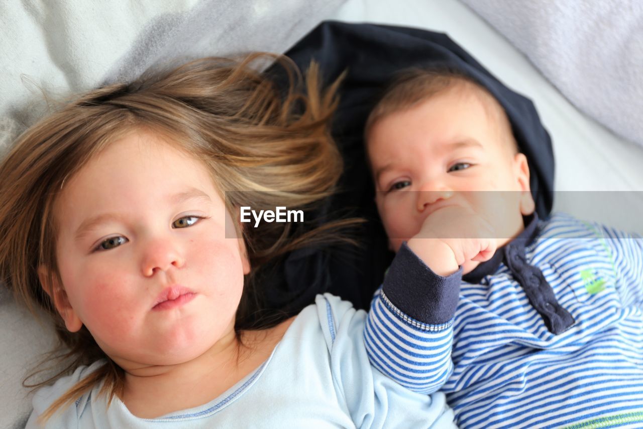 Portrait of cute siblings lying on bed