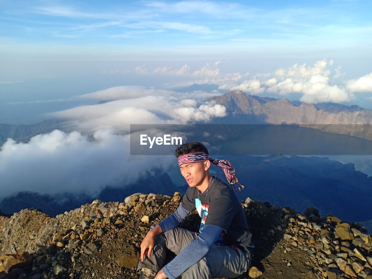 Man sitting on mountain against sky