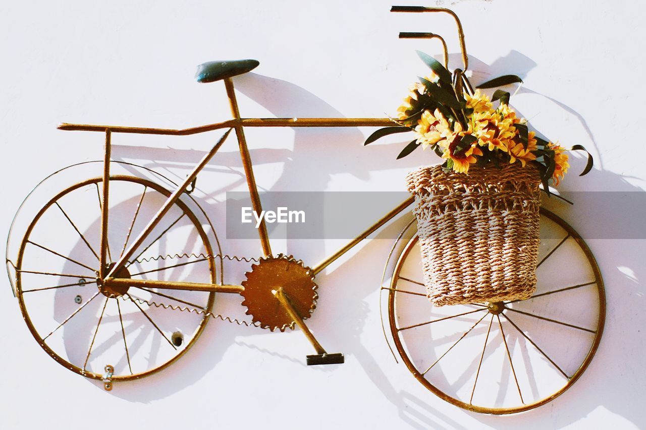 Close-up of bicycle shaped metallic decoration with flowers in basket on wall