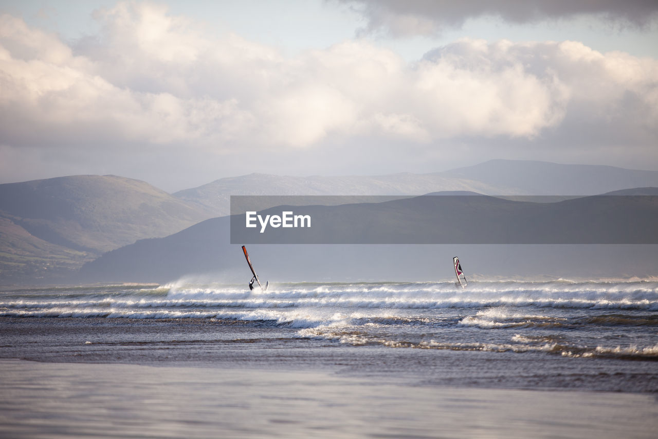 Windsurfing on beach against sky