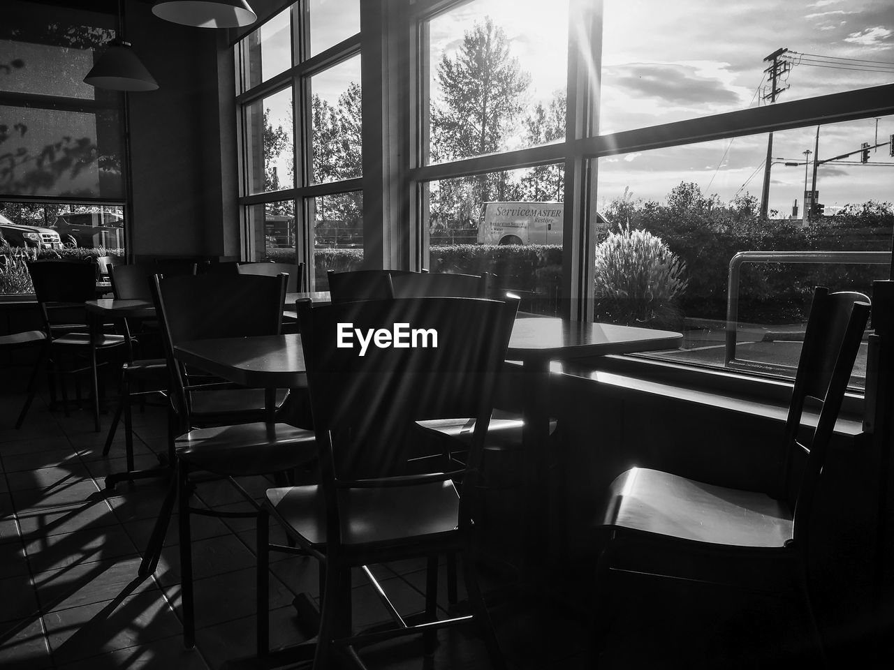 EMPTY CHAIRS AND TABLES IN GLASS WINDOW