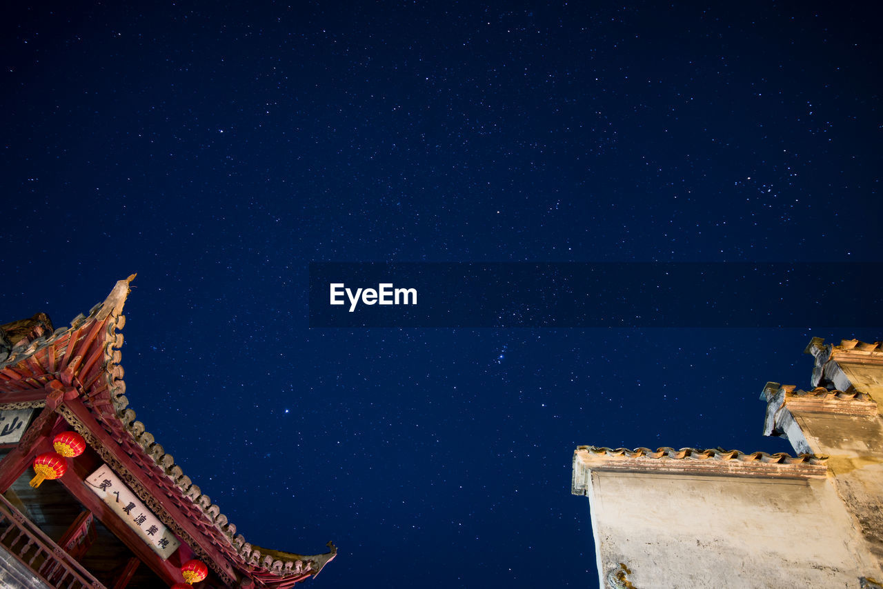 Low angle view of buildings against star field at night