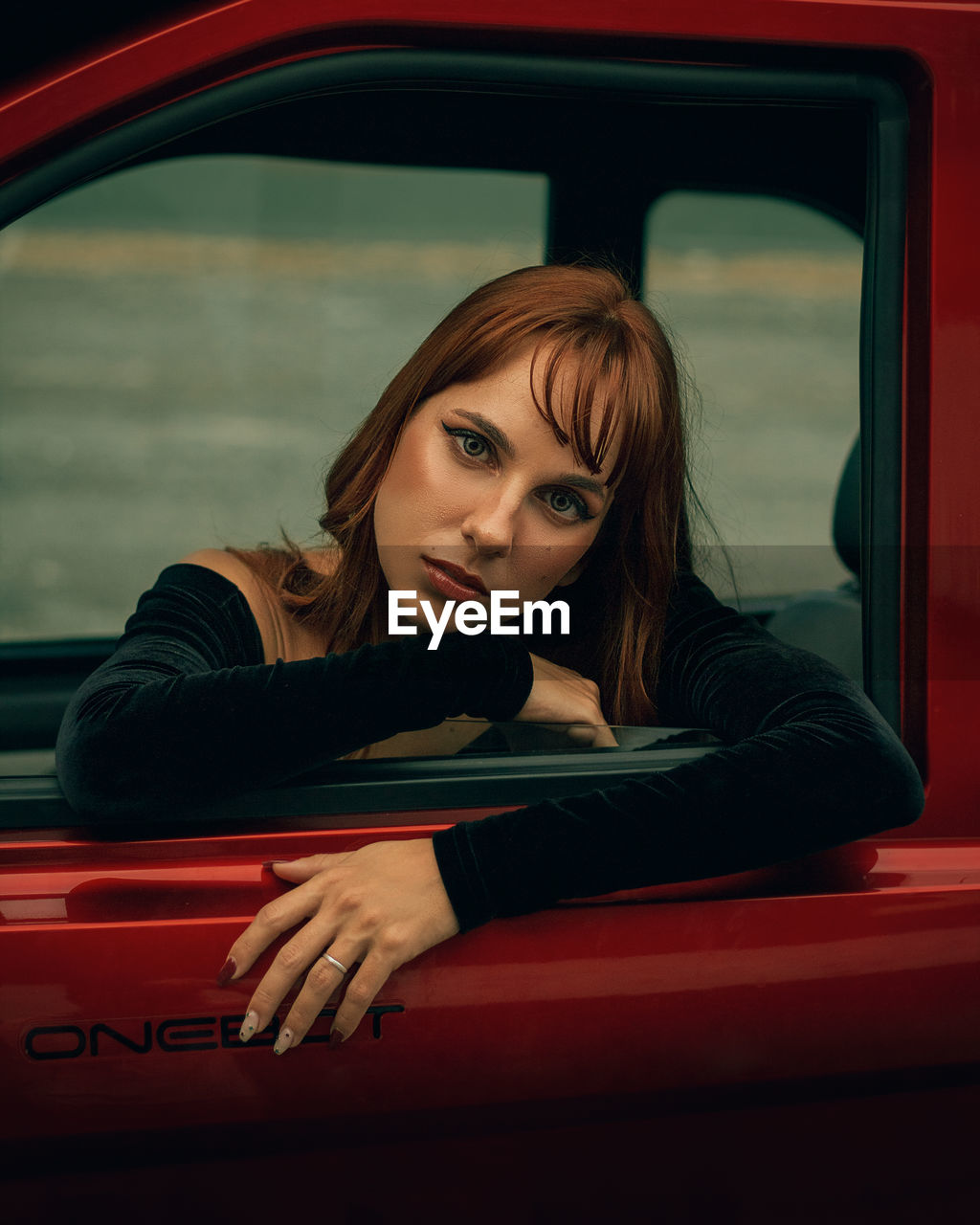 Portrait of a beautiful young woman sitting in car and looking at the camera with a penetrating gaze