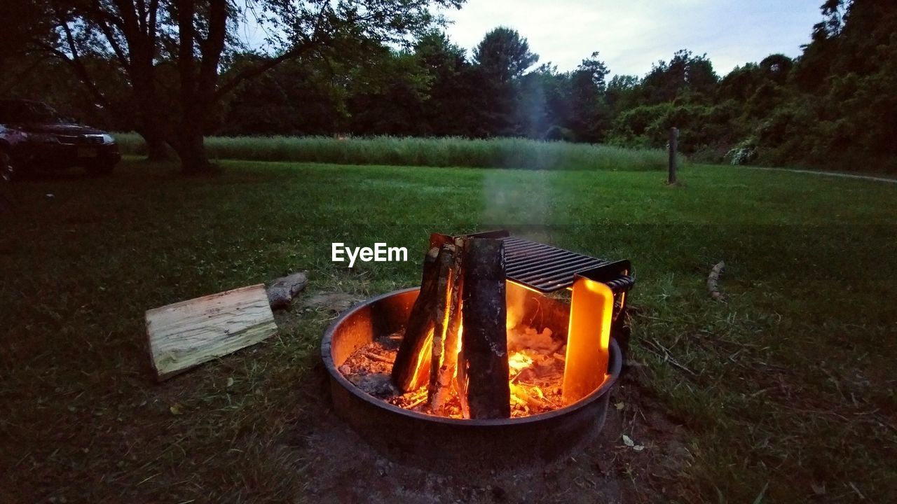 High angle view of barbecue grill over fire on grass against trees