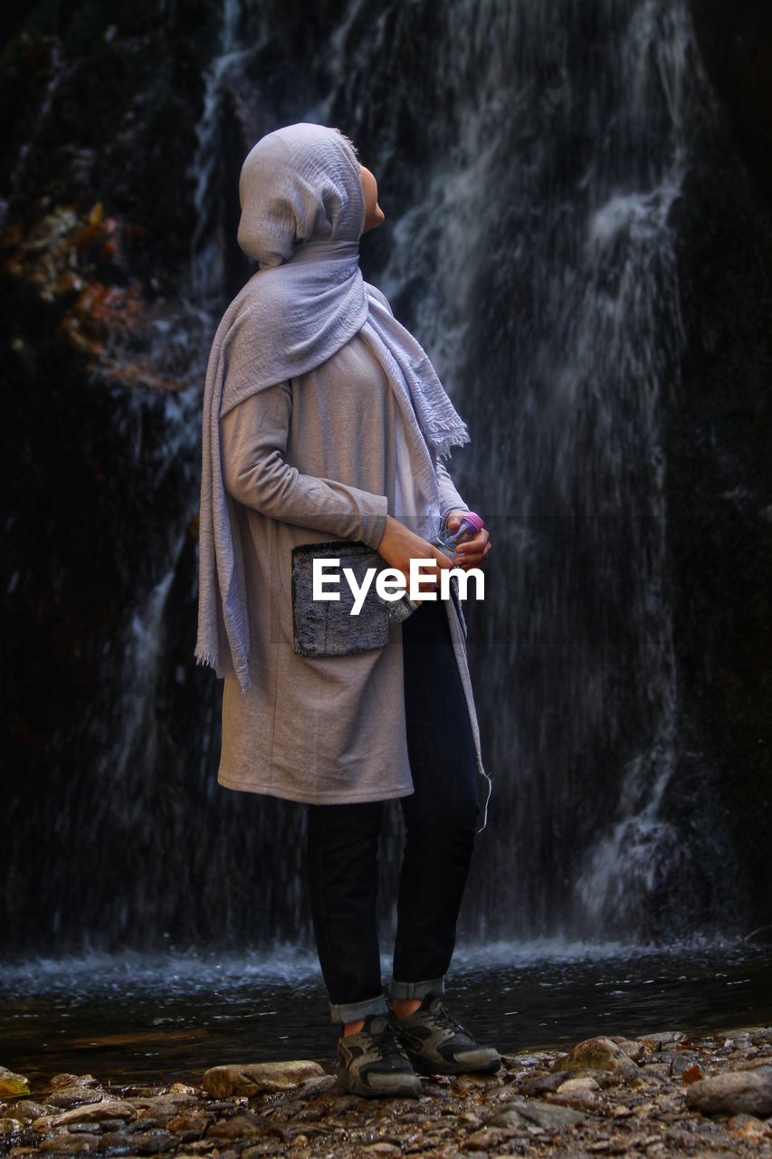 Woman standing by waterfall in forest