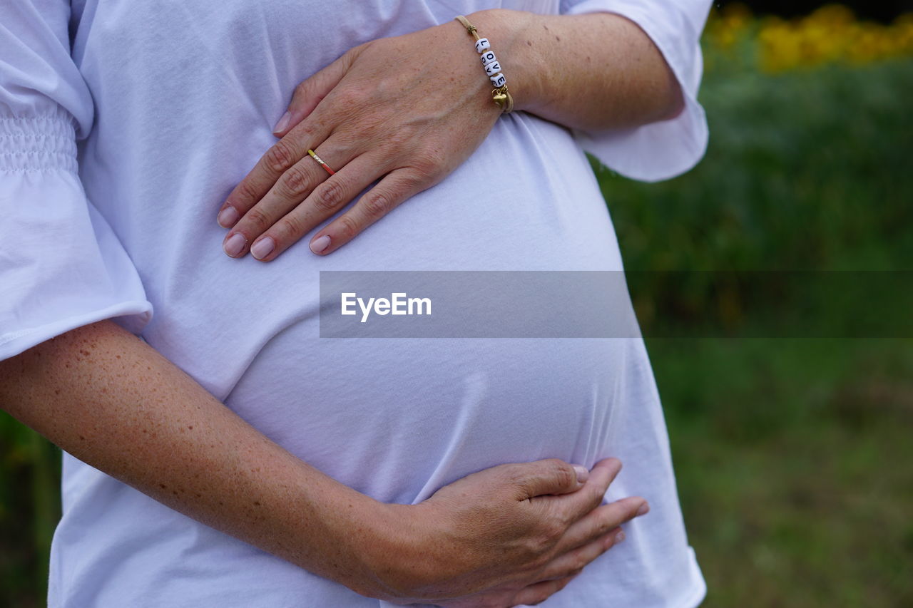 Midsection of pregnant woman touching abdomen