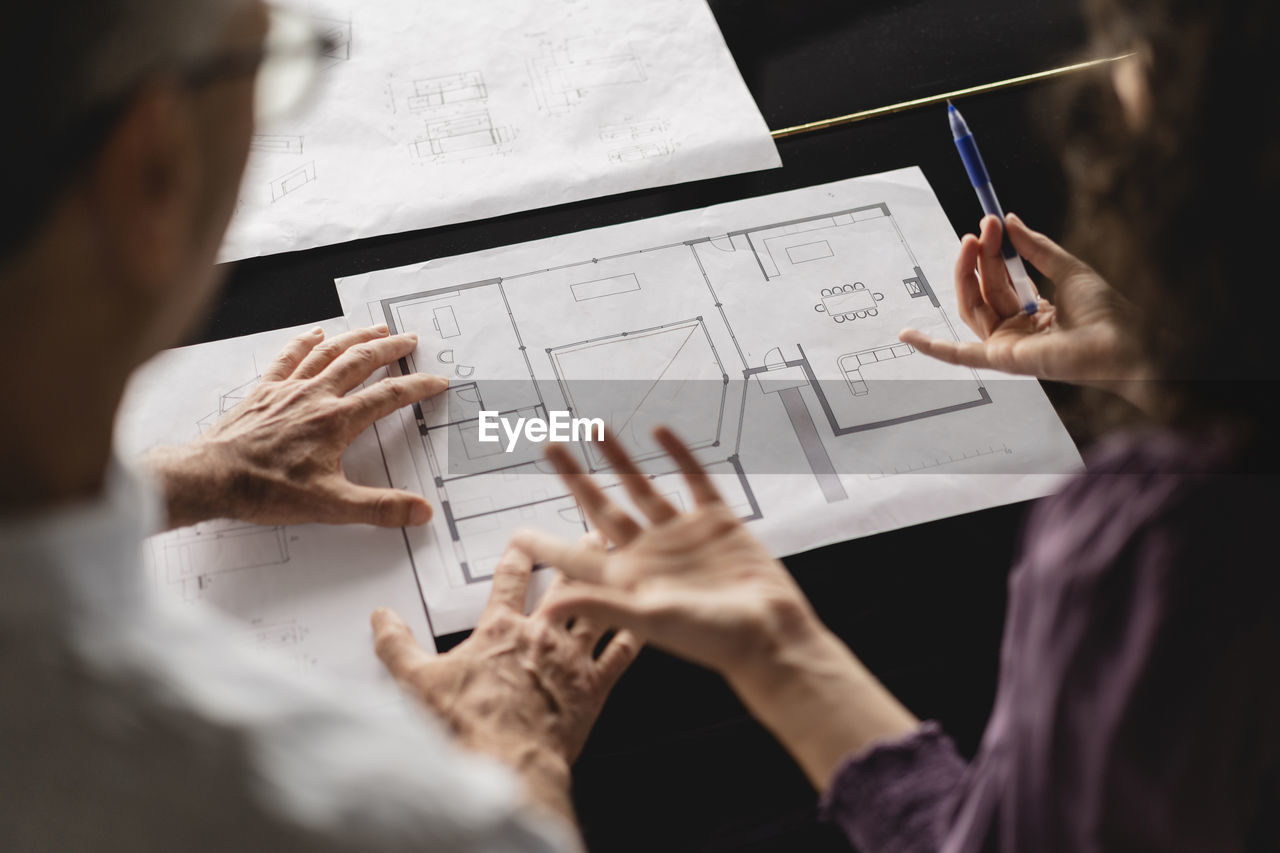 Business colleagues discussing over floor plan on table at office