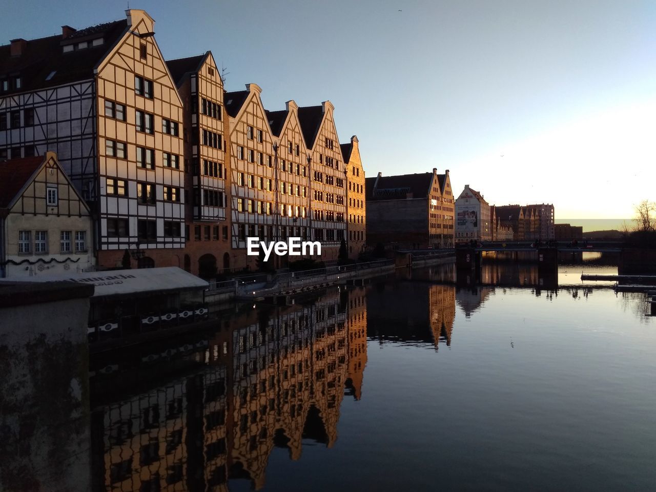 REFLECTION OF BUILDINGS ON RIVER AGAINST SKY