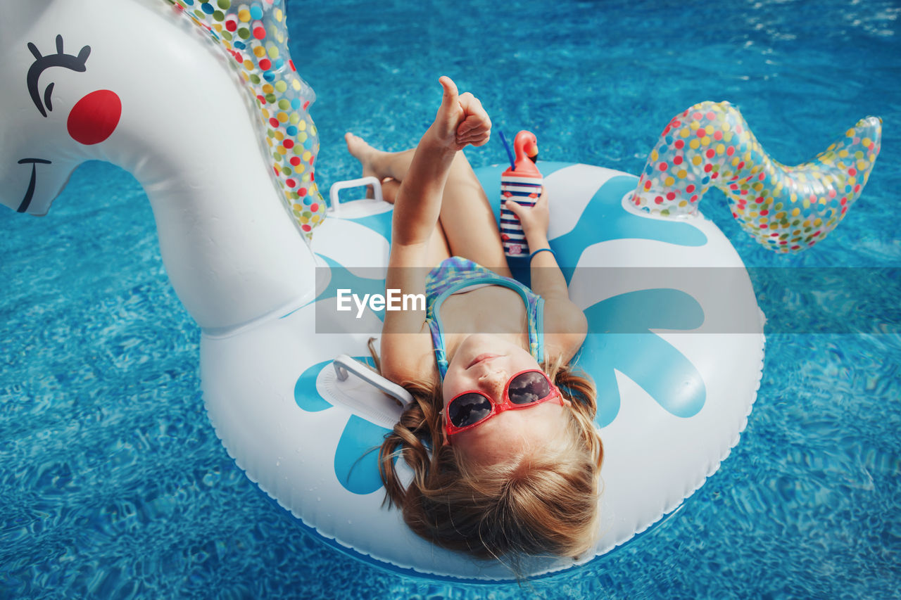 HIGH ANGLE VIEW OF WOMAN WEARING SUNGLASSES SWIMMING POOL