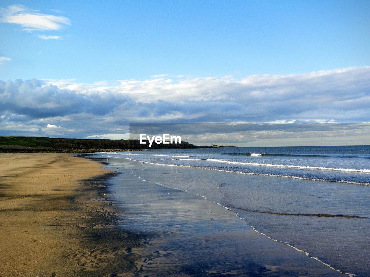 Scenic view of beach against cloudy sky