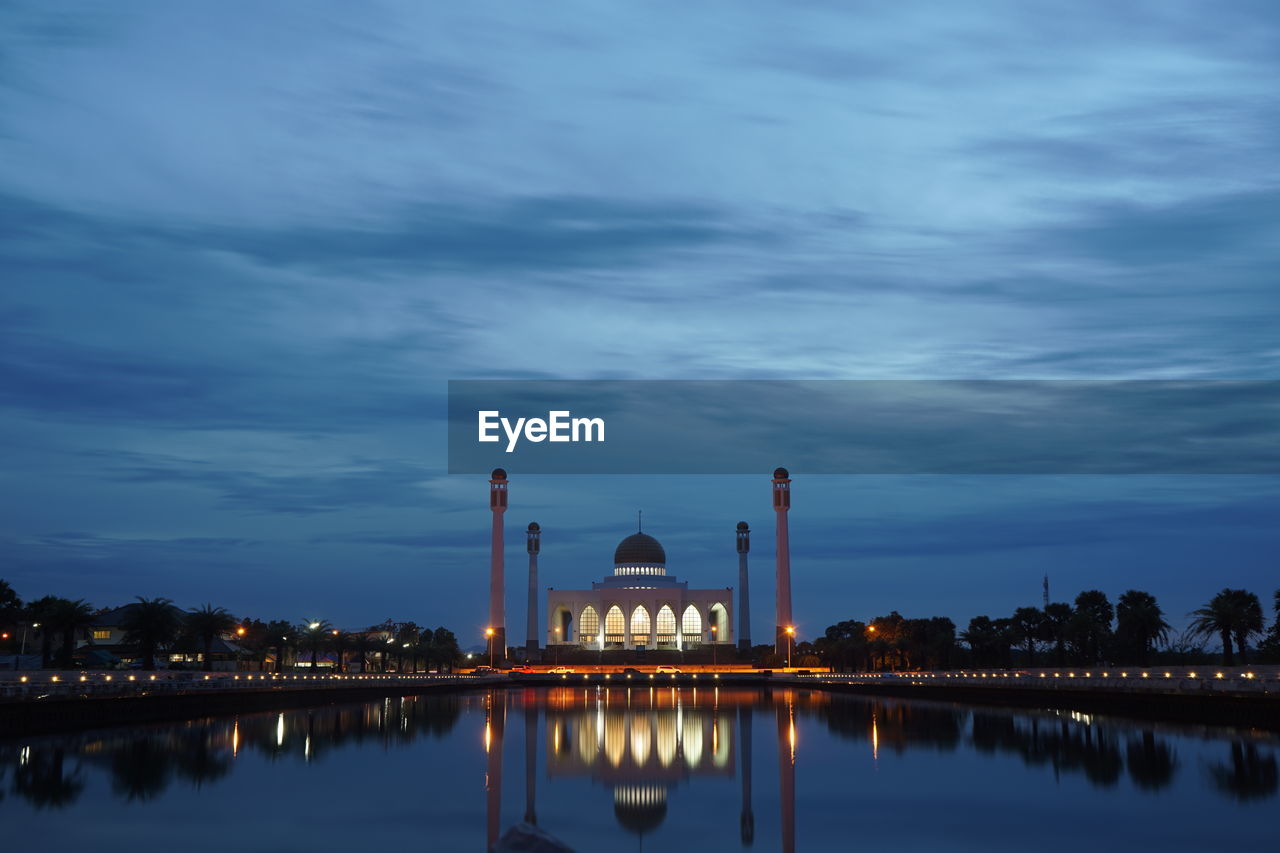 Mosque reflecting in lake against sky at dusk