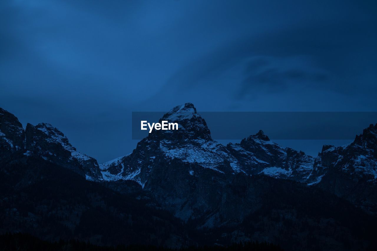 Scenic view of snowcapped mountains against blue sky at night